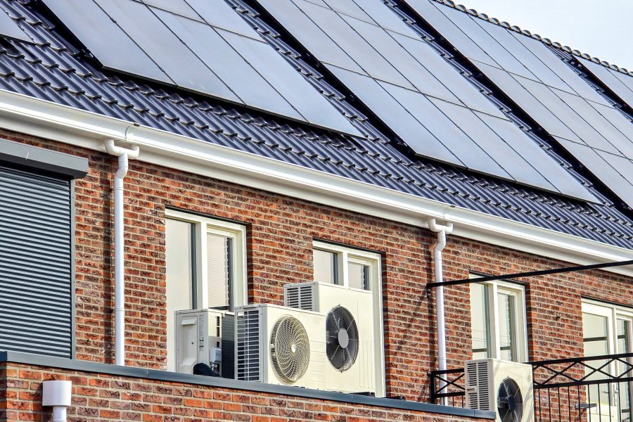 air source heat pump unit installed outdoors at a modern home with solar panels in the Netherlands, new house with black solar panels. Zonnepanelen, Zonne energie, Translation: Solar panel, Sun Energy
